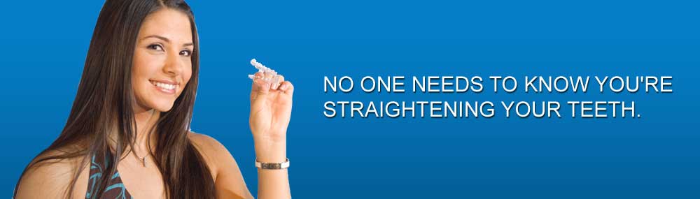 A smiling woman holding a clear aligner
